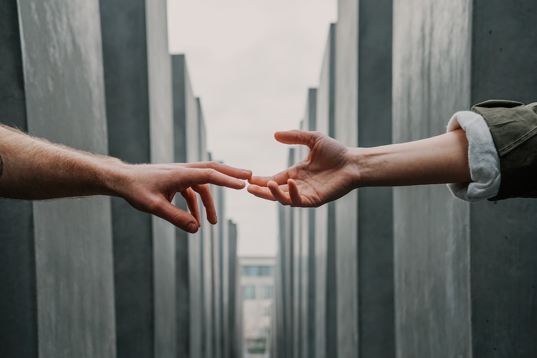 Two people reaching for each other in front of a memorial.