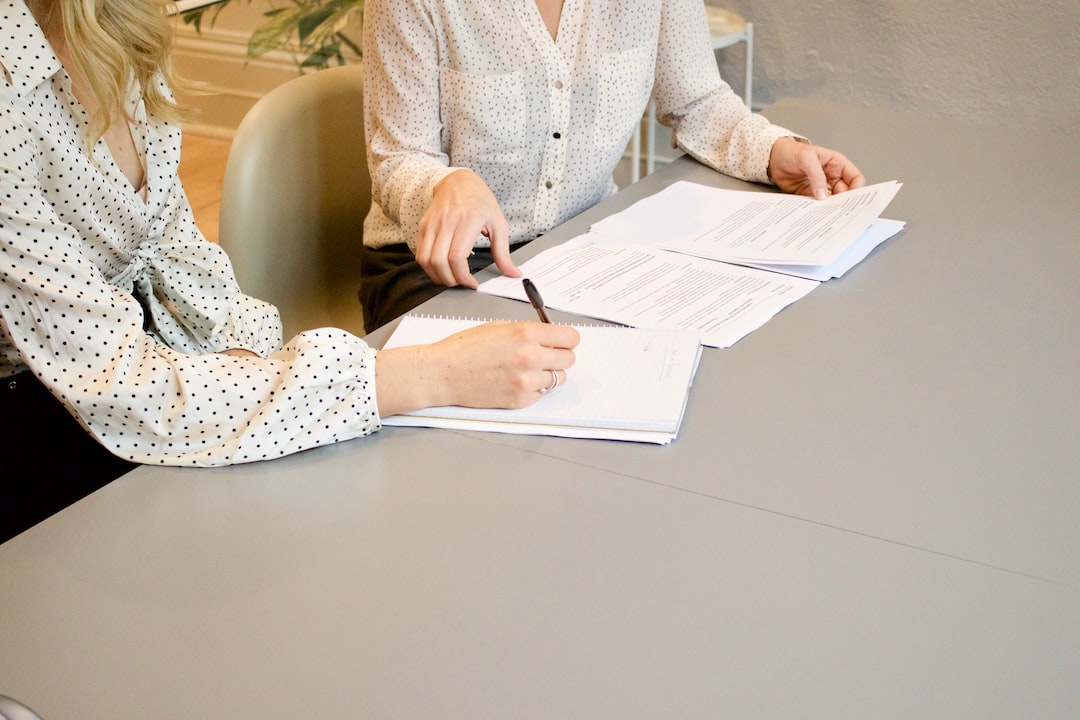 Two women sitting at a table signing papers.