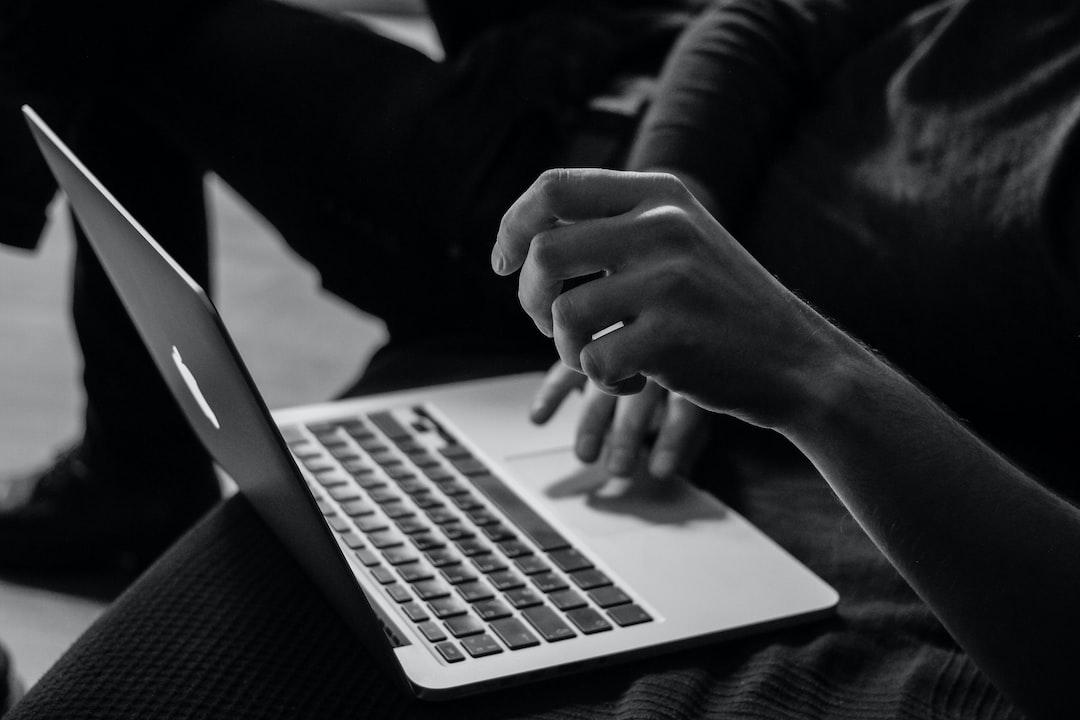 A black and white photo of a person using a laptop.