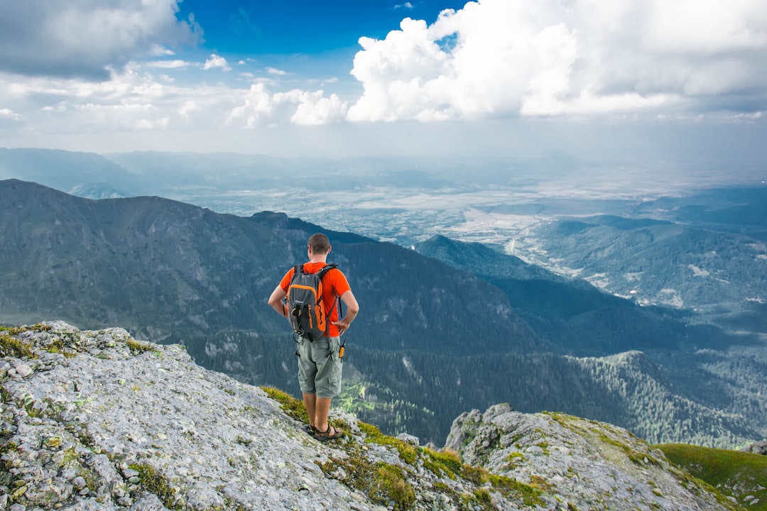 A man is standing on top of a mountain overlooking a valley.