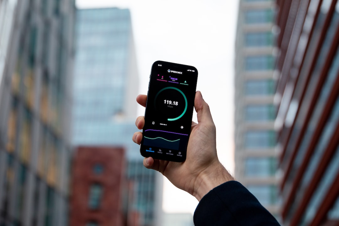 A man holding up a smartphone with a fitness tracker on it.