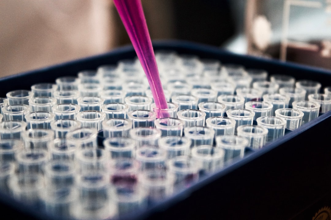 A person is pouring a pink liquid into a test tube.