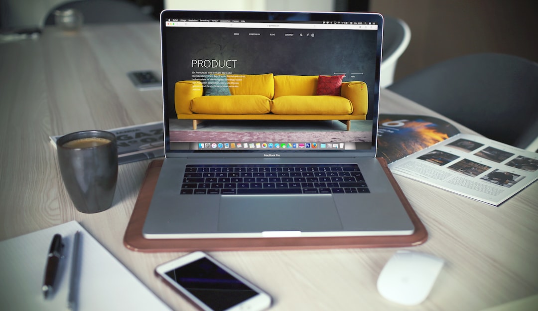 A laptop with a yellow couch on it sitting on a desk.