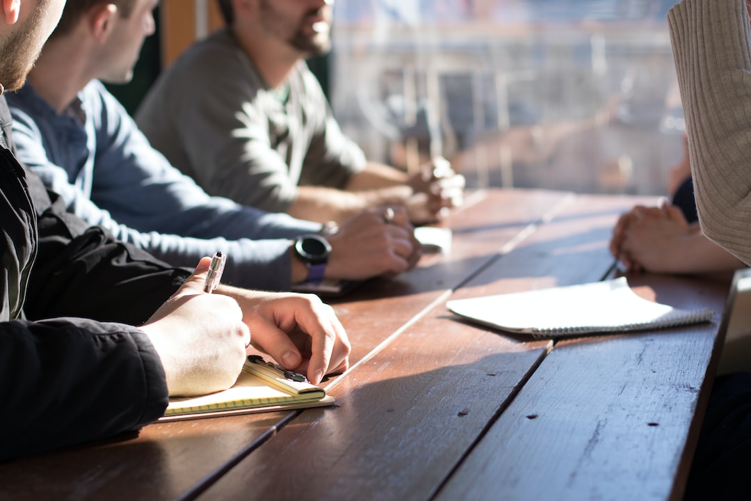 A group of people sitting around a wooden table.