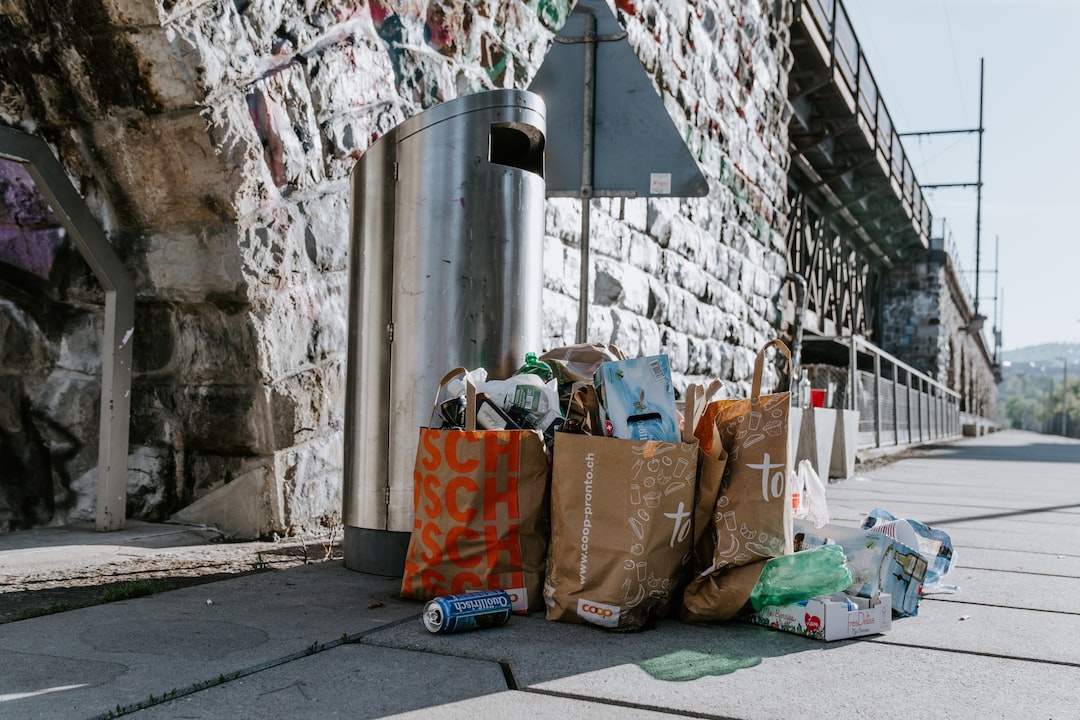 A group of garbage bags on a sidewalk next to a bridge.