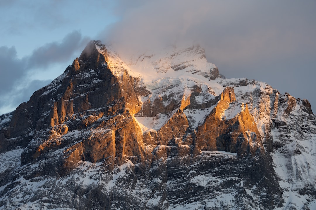 A mountain covered in snow with the sun shining down on it.