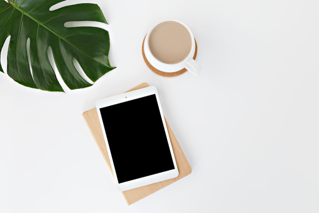 A tablet computer and a cup of coffee on a white table.