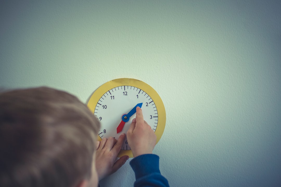 A boy is putting a clock on the wall.