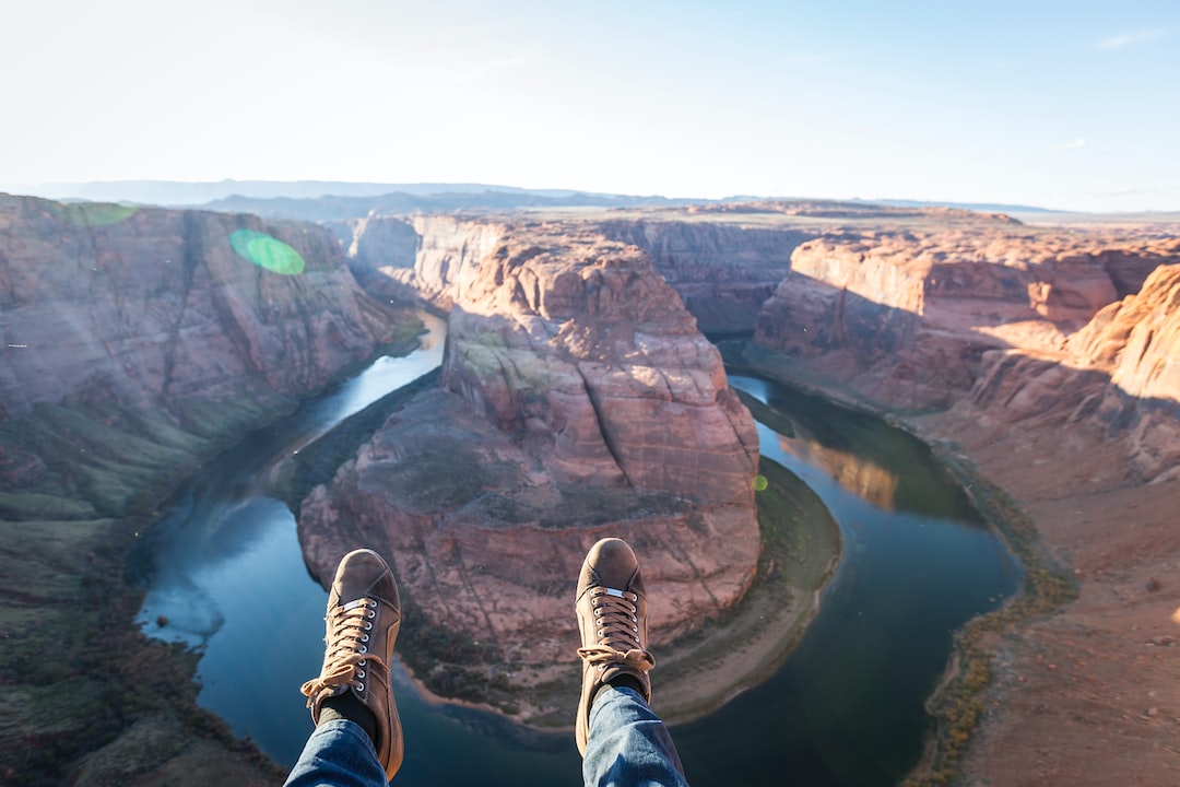 The feet of a person standing on the edge of a canyon.