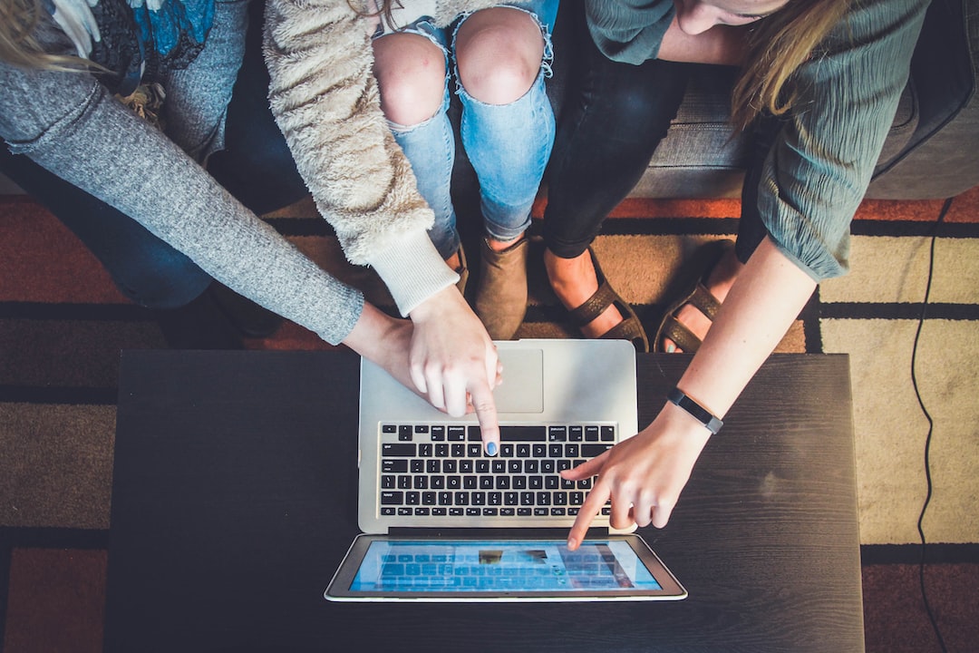 A group of friends sitting around a laptop.