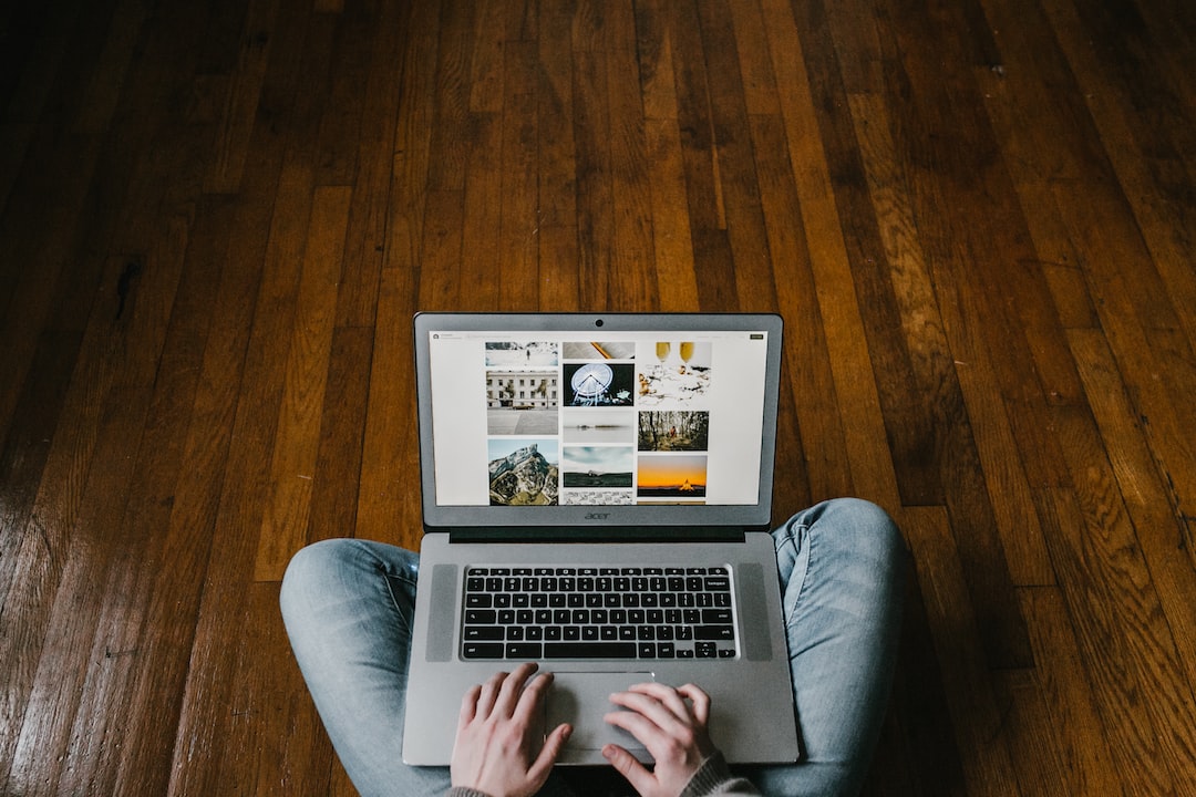 A person sitting on a wooden floor with a laptop.