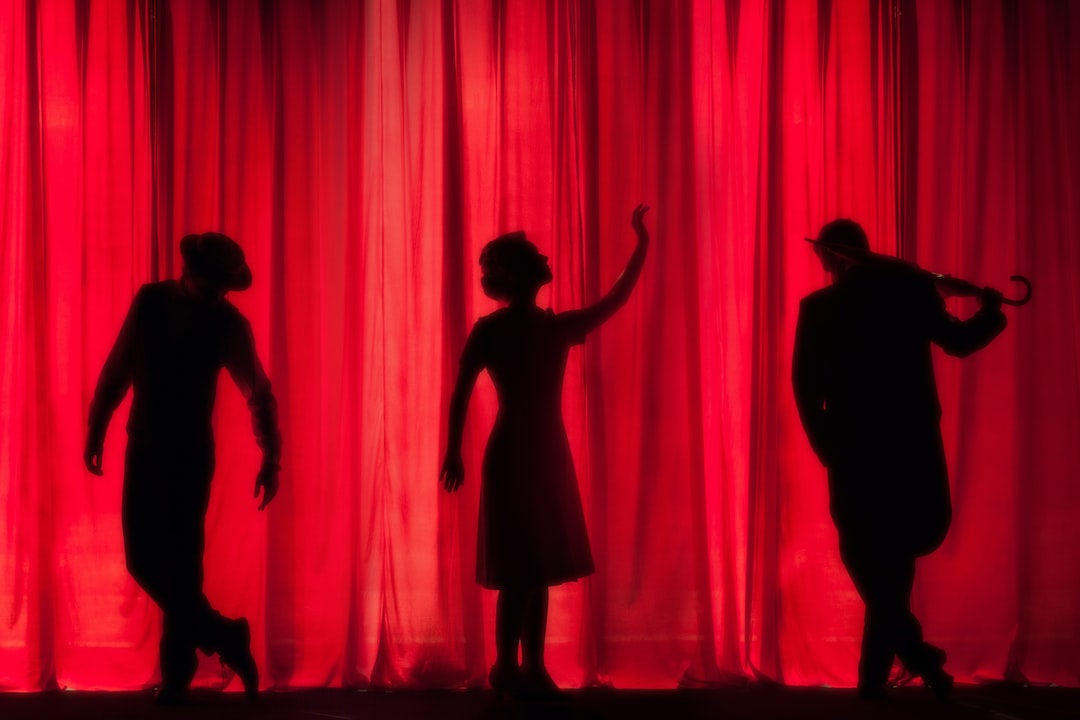 Silhouettes of people dancing in front of a red curtain.