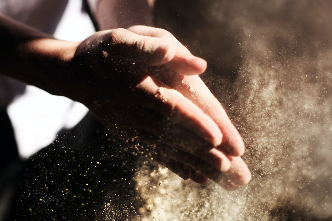 A person's hand is sprinkling sand into the air.